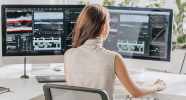 back view of filmmaker working near computer monitors